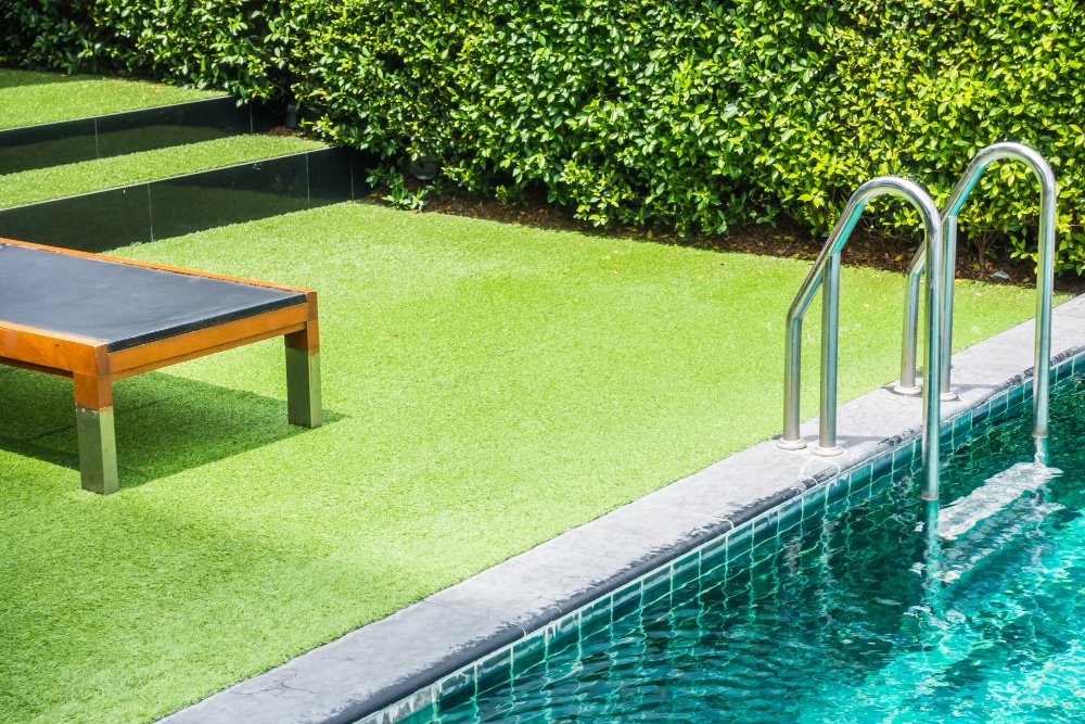A synthetic grass installation beside a modern Ottawa pool, offering a soft and stylish space for barefoot lounging.