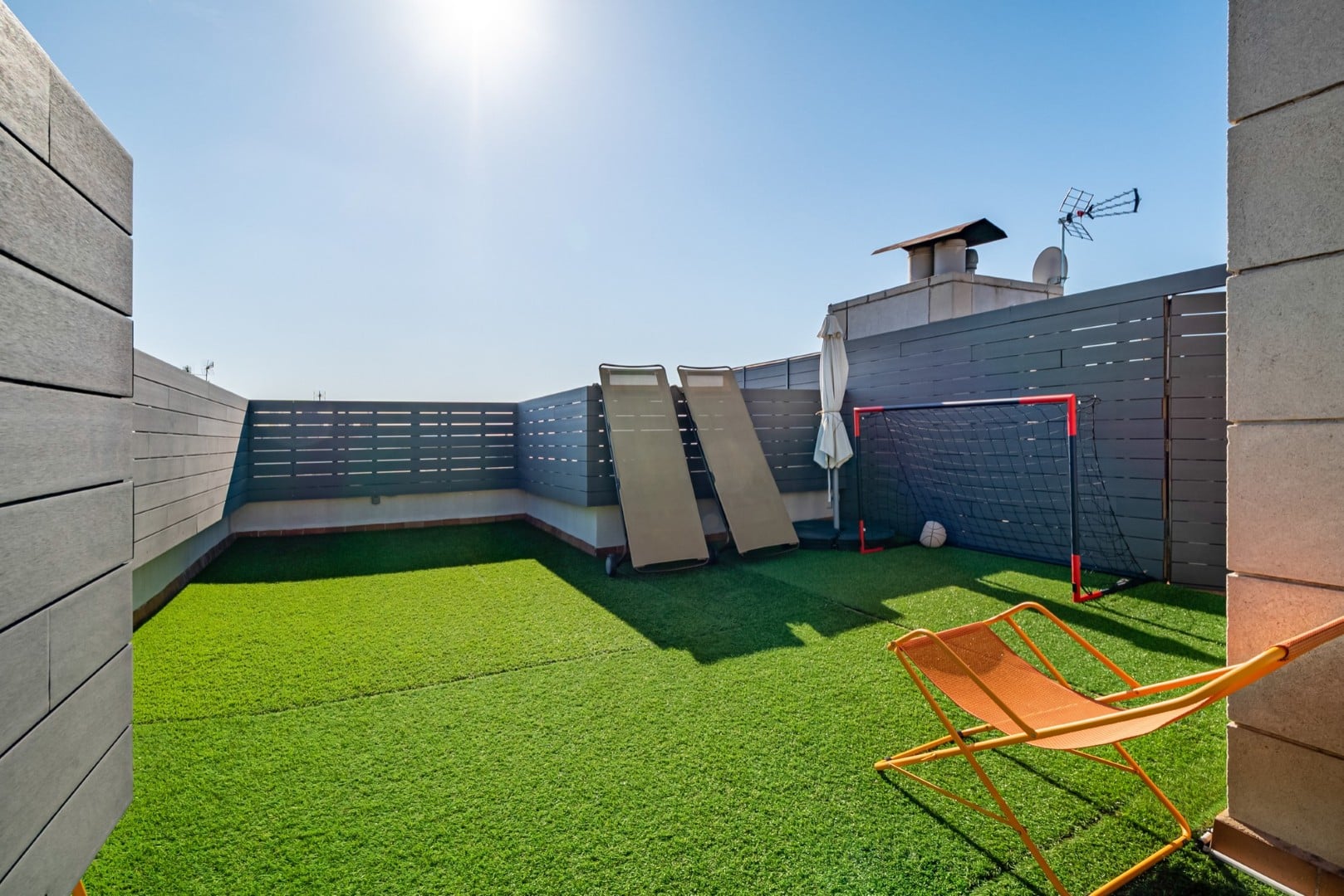 A rooftop play zone in Ottawa featuring synthetic grass, a slide, and seating, ideal for urban families seeking low-maintenance outdoor space.